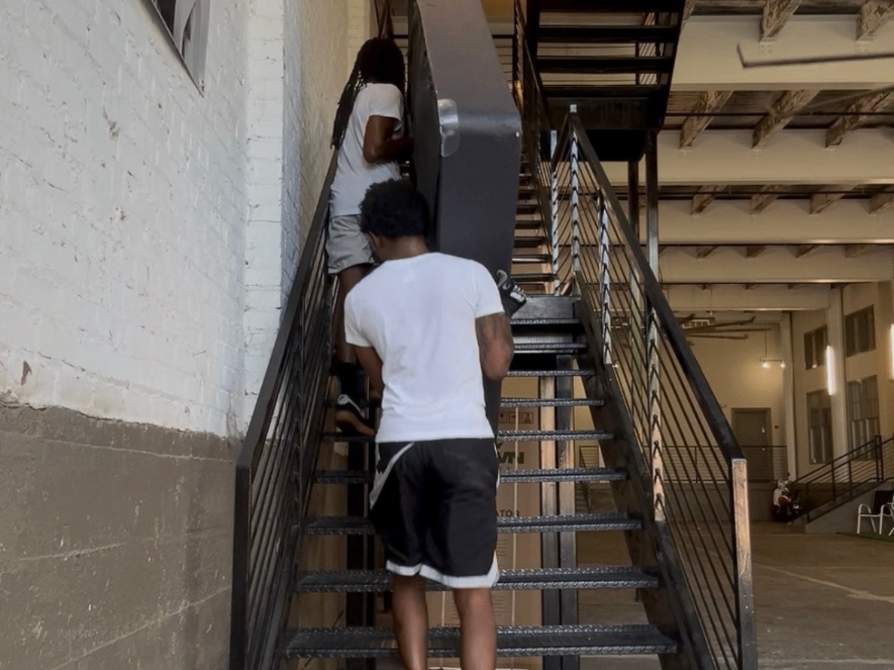 Movers carrying a cabinet up a stairwell